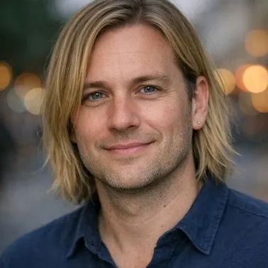 Man in late 30s, blonde shoulder-length hair, grey-blue eyes, calm expression